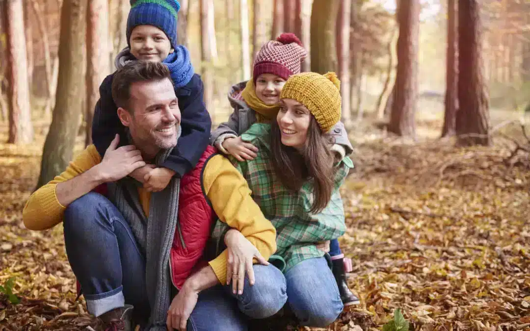 Une famille souriante se promène en forêt à l'automne près de Vernon, Eure, non loin de leur hébergement touristique. Les feuilles mortes craquent sous leurs pas, et les arbres se parent de couleurs automnales. Un moment de détente en pleine nature pour petits et grands