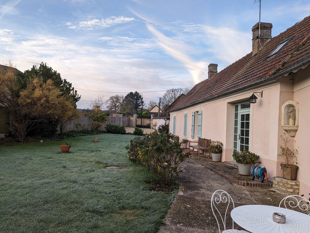 Image extérieure de la Maison de Gisèle en hiver, vue depuis le jardin, mettant en lumière l'architecture normande dans un cadre enchanteur.